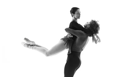 Synchronized elegance. Male and female ballet partners in practice against white studio background. Black and white filter. Concept of pair training, classic ballet, inspiration, beauty, creativity.の写真素材