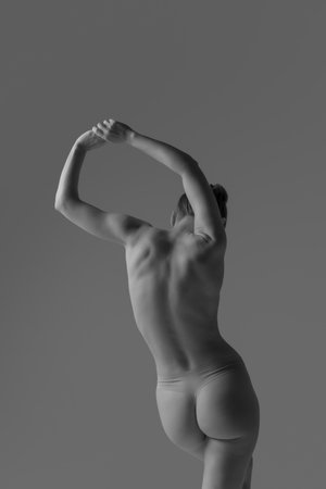 Grayscale photo. Back view of woman stretching gracefully, shows contours of her muscular frame. Elegance and strength of human form. Concept of beauty, skincare, body care, healthcare, medicine. adの写真素材