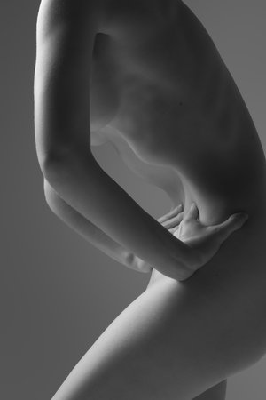 Black and white photo. Partially obscured nude f woman in dynamic pose, shoe curve of torso and hand gripping side. Fit body. Concept of beauty, skincare, body care, healthcare, medicine.の写真素材