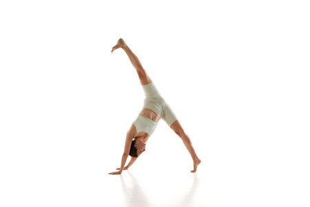 Sporty woman in athletic wear performs one-legged downward dog yoga pose demonstrating her...