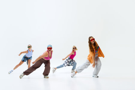 Lively quartet of dancers, wearing colorful streetwear and sunglasses, pose energetically against white studio background. Concept of music, fashion and art, retro and modernity, sport and hobby. Adの写真素材