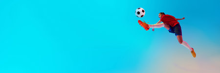 Banner. Dynamic photo of female soccer player in action kicks ball in neon light against blue gradient background with negative space. Concept of women and sport, team games, movement, victory, actionの写真素材
