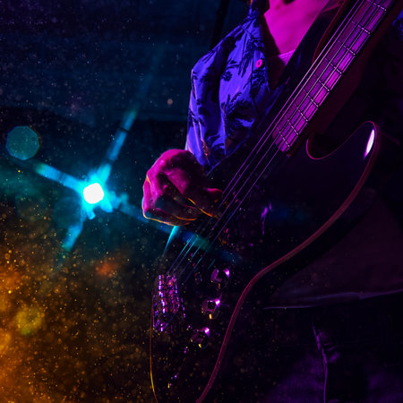 Intensity of live music captured in guitarists hand, bathed in vibrant hues of stage lights as he strum strings. Concept of music and party, hobby and work, energy, music festivals. Adの写真素材