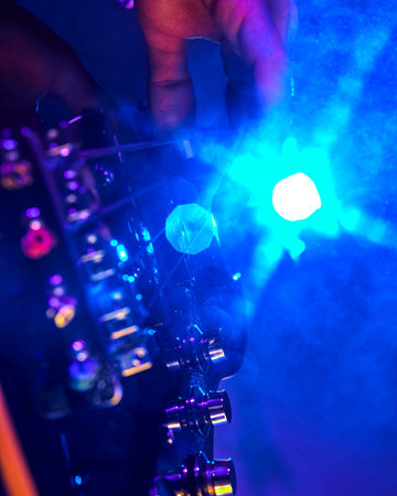 Guitarists fingers dance across strings, highlighted by bold blue and purple lights, encapsulating passion of live music. Concept of party, hobby and work, energy, music festivals. Adの写真素材