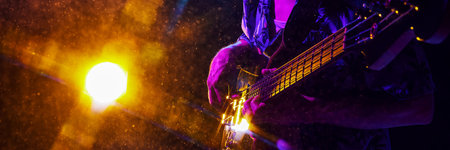 Banner. Musicians hand strums guitar, highlighted by electric blue and purple lights, creating vivid scene of musical passion. Concept of music and party, hobby and work, energy, music festivals. Adの写真素材