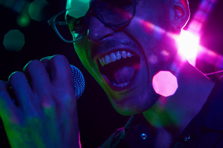 Vibrant neon hues highlight the intensity of vocalist in heat of performance, his powerful voice visible in every detail. Concept of music and party, hobby and work, energy, music festivals. Adの写真素材