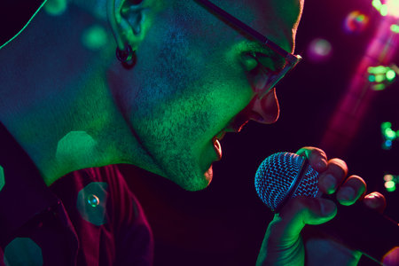 Vocalists face, glowing under neon lights, show raw emotion and energy of live music, with every detail of performance visible. Concept of music and party, hobby and work, energy, festivals. Adの写真素材