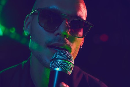 Close-up photo of singers face, his expression full of intensity and passion, bathed in neon lights during powerful performance. Concept of music and party, hobby and work, energy, music festivals.の写真素材