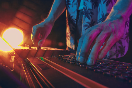 Close-up of hands tweaking mixer, warm glow of lights reflecting off dials, setting vibe for unforgettable night of music. Concept of music and party, hobby and work, energy, music festivals. Adの写真素材