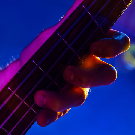 Neon stage lights illuminate musicians hand in midst of guitar solo, capturing essence of live rock performance. Concept pf music and party, hobby and work, energy, music festivals. Adの写真素材