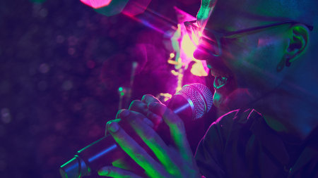 Vivid glow of stage lights casts dramatic shadow on singers face, capturing raw emotion of live performance. Concept of music and party, hobby and work, energy, music festivals. Adの写真素材