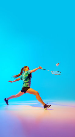 Young woman, badminton athlete leaping in motion to hit shuttlecock with rocket in neon light against gradient blue background. Concept of individual sport, tournament, match, championship. Adの写真素材