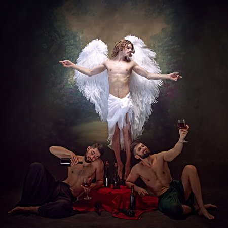 Angel flying and glowing in light, while two men indulge in wine beneath him, illustrating contrast between purity and indulgence. Concept of classic art, renaissance, light and dark.の写真素材