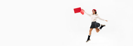 Woman in red beret and matching shopping bag, woman leaps forward joyfully against white background with negative space. Concept of shopping, Black Friday, fashion and style, sale season. Adの写真素材