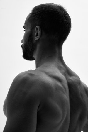 Close-up of mans muscular back, well-defined shoulders, monochrome filter highlight his strong physique, creating sense of power. Concept of beauty and fashion, style and youth, male health.の写真素材