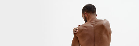 Banner. Rear view of man holding hand on shoulder as he feels pain in joints against white background with negative space. Concept of beauty and fashion, style and youth, male health.の写真素材