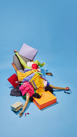 Woman buried under chaotic pile of colorful clothes, symbolizing overwhelming nature of Black Friday shopping madness. Concept of sales season, Black friday, holidays shopping. Pop art style.の写真素材