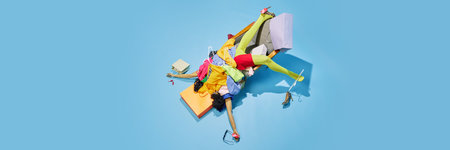 Shopper collapsed under heap of clothes and bags, representing chaotic and humorous aftermath of...
