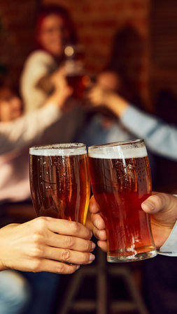 Cheers to game. Friends gather, drinks in hand, while background buzzes with energy. Bar atmosphere captures perfect sports celebration. Concept of Oktoberfest, brewery, vacation, Friday mood.の写真素材