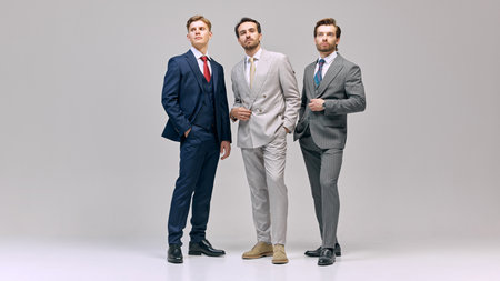 Three young man standing poised, each displaying individual style unified in professionalism against...