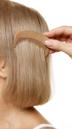 Careful hand combs through her silky hair, highlighting care and attention to detail against white studio background. Concept of beauty, wellness, cosmetology, anti-aging products. Adの写真素材