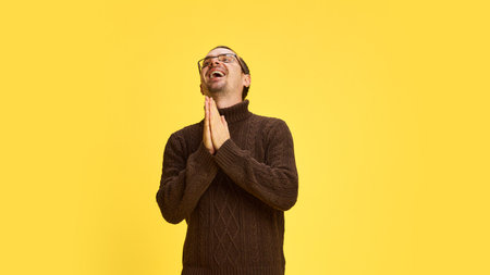 Man with hands in a prayer gesture, smiling warmly gesturing gratitude and thankfulness and...