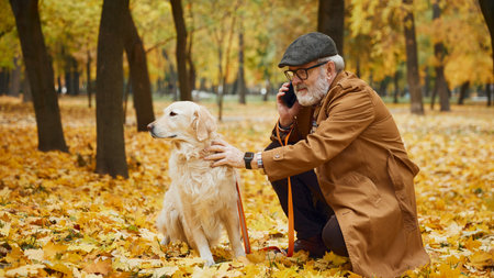 Elderly man, dressed vintage attire, and dog at park, autumn loves underfoot creating warmth, golden carpet. Concept of mature people in modern lifestyle, recreation, retirement time.の写真素材