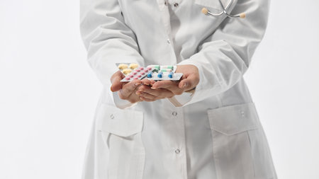 Cropped image of young medical therapist holding blisters of medical treatments against white studio background. Pharmaceutical. Concept of medicine, health care, work. Adの写真素材
