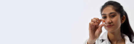 Banner. Portrait of of young attractive woman demonstrate one pill against white studio background...