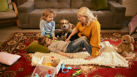 Grandmother watching as children practice medical checks on brother, encouraging understanding of care and treatment through play. Concept of knowledge about healthy lifestyle and medicine.の写真素材