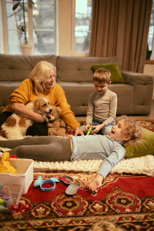 Grandmother with children sitting on carpet exploring medical toys, encouraging knowledge about healthy habits, medical procedures, and health check-ups. Concept of knowledge about medicine.の写真素材