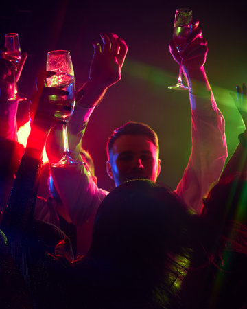 Stylish movements and radiant smiles take center stage as group of friends celebrates under neon lights, toasting to unforgettable memories. Concept of party, youth, carefree, celebration. adの写真素材
