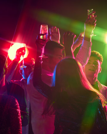 Happy birthday celebration. Champagne glasses shimmer as crowd dances under glowing lights, marking...