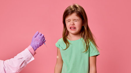 Tearful girl with closed eyes with bandage on arm and doctors hand holding syringe, evoking emotions against pink studio background. Concept of healthcare, protection, immunity, prevention.の写真素材