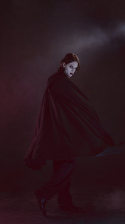 Lord of darkness. Man in black cape, looks terrifying as vampire, spins dramatically, turning his...