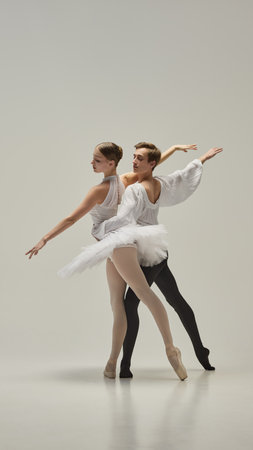 Ballet partners moving in perfect harmony, arms extended with fluid motion, bodies intertwining in elegant balance against white studio background. Concept of grace, art, beauty, classic.の写真素材