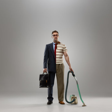 Composite image. Man in business suit on one side and casual clothes with vacuum cleaner on other, standing confidently on grey background. Office work and home duties. Concept of work-life balanceの写真素材
