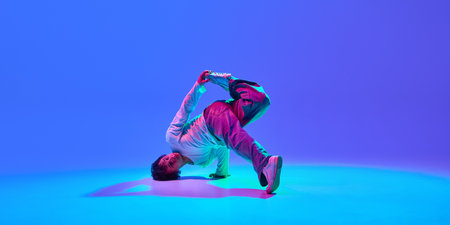 Dynamic image of energetic young guy, breakdancer in motion, performing, showing skills against...
