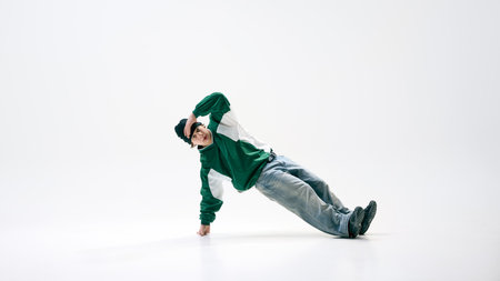 Full-length photo of athletic breakdance, dressed vibrant vintage attire, performing handstand shows strength against white studio background. Concept of self-expression, modern street culture.の写真素材