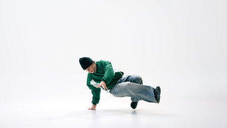 Breakdancer in fluid motion with legs kicking sideways while maintaining control against white...
