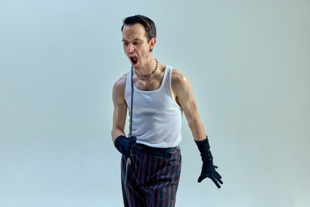 Fierce expression radiating raw emotion, artist gripping cane tightly as if channeling passion into powerful vocal performance against soft-toned backdrop. Concept of art, music, vintage, talentの写真素材