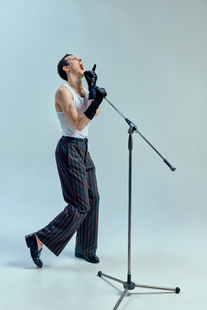 Passionate vocalist lost in performance, mouth open in intense expression as if pouring soul into music, gripping microphone in emotional crescendo. Concept of art, music, vintage, talentの写真素材