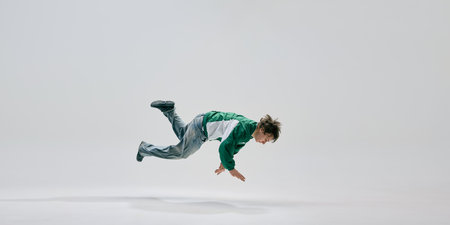 High-energy dancer, dressed vibrant retro clothes, captured mid-air showcasing extreme control and agility against white studio background. Concept of athleticism, freestyle, expression, skill, power.の写真素材