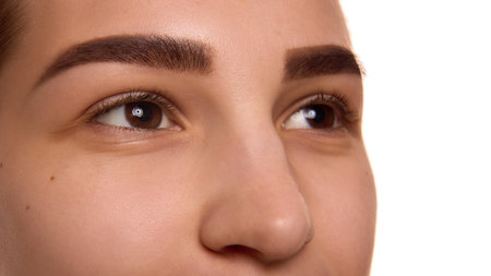 Extremely close up of young woman with well-groomed brows, long lashes and well-kept healthy skin against white background. Concept of youth and natural beauty, cosmetology treatment, cosmetic, spa.の写真素材