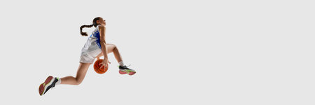 Banner. Focused young athlete girl, basketball player performing slam dunk in motion against white...