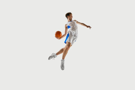 Sharp action. Young athlete, basketball player rotating mid-air, ball held behind back, body...