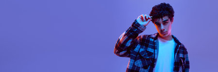 Banner. Teen boy lifting glasses with serious face, showing questioning, puzzled expression in neon light against gradient background with negative space. Concept of digital youth, education, fashionの写真素材