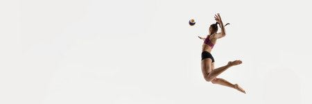 Banner. Side view of jumping woman about to hit volleyball against white studio background with negative space to insert text. Copy space. Concept of sport events, championship, timing, serve positionの写真素材