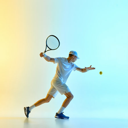 Tennis player following through forehand strike in mid-swing against vibrant blue-yellow gradient background in warm neon light. Concept of fast-paced action, match intensity, game control.の写真素材