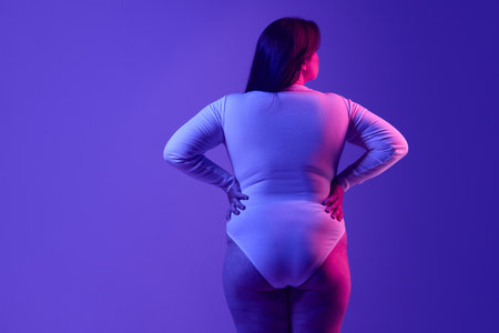 Back view of plus-size woman exuding confidence and empowerment, showcased with bold visual contrast in an editorial style. Concept of body positivity and empowerment.の写真素材